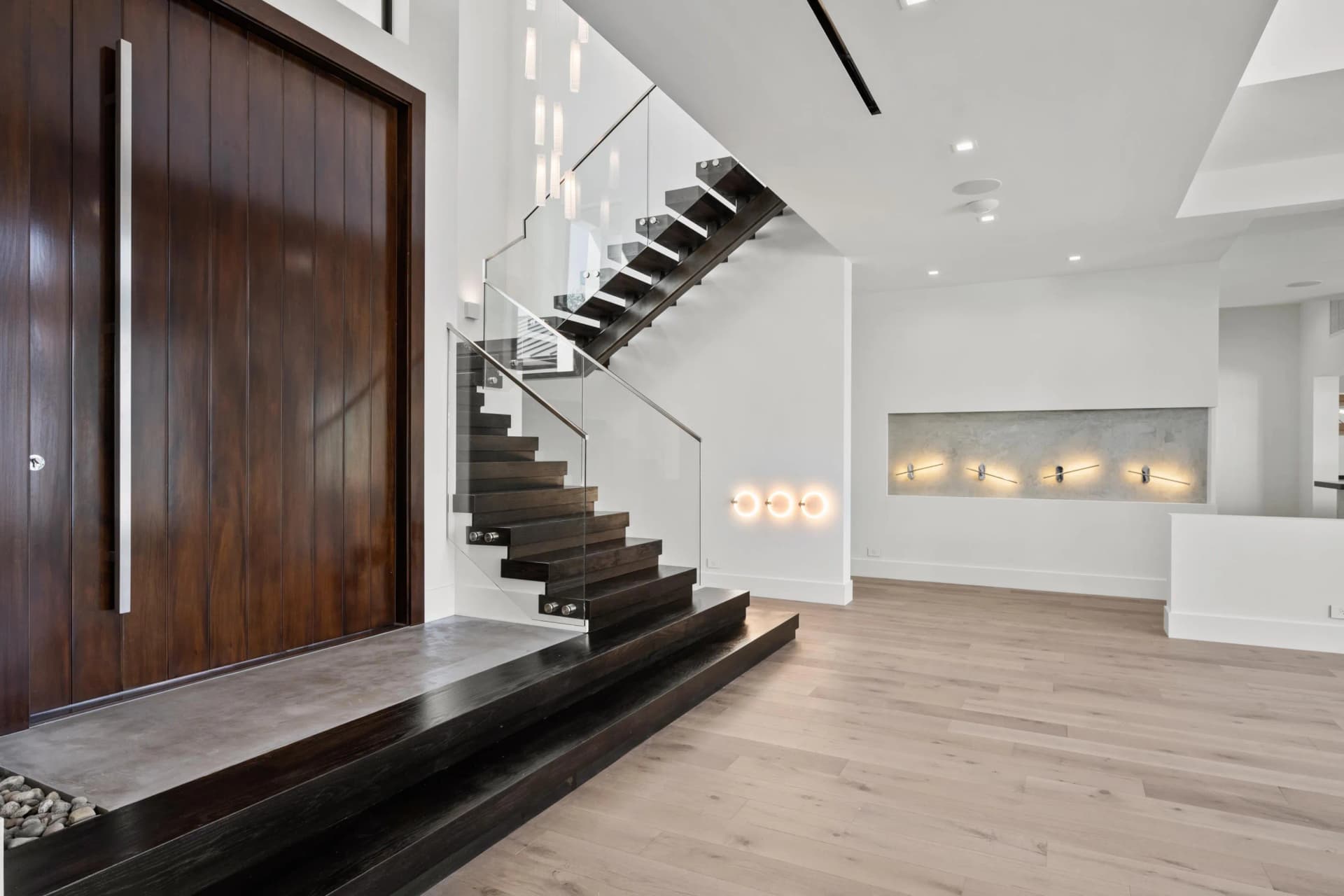 Foyer with floating staircase, walnut entry door, and illuminated niche wall